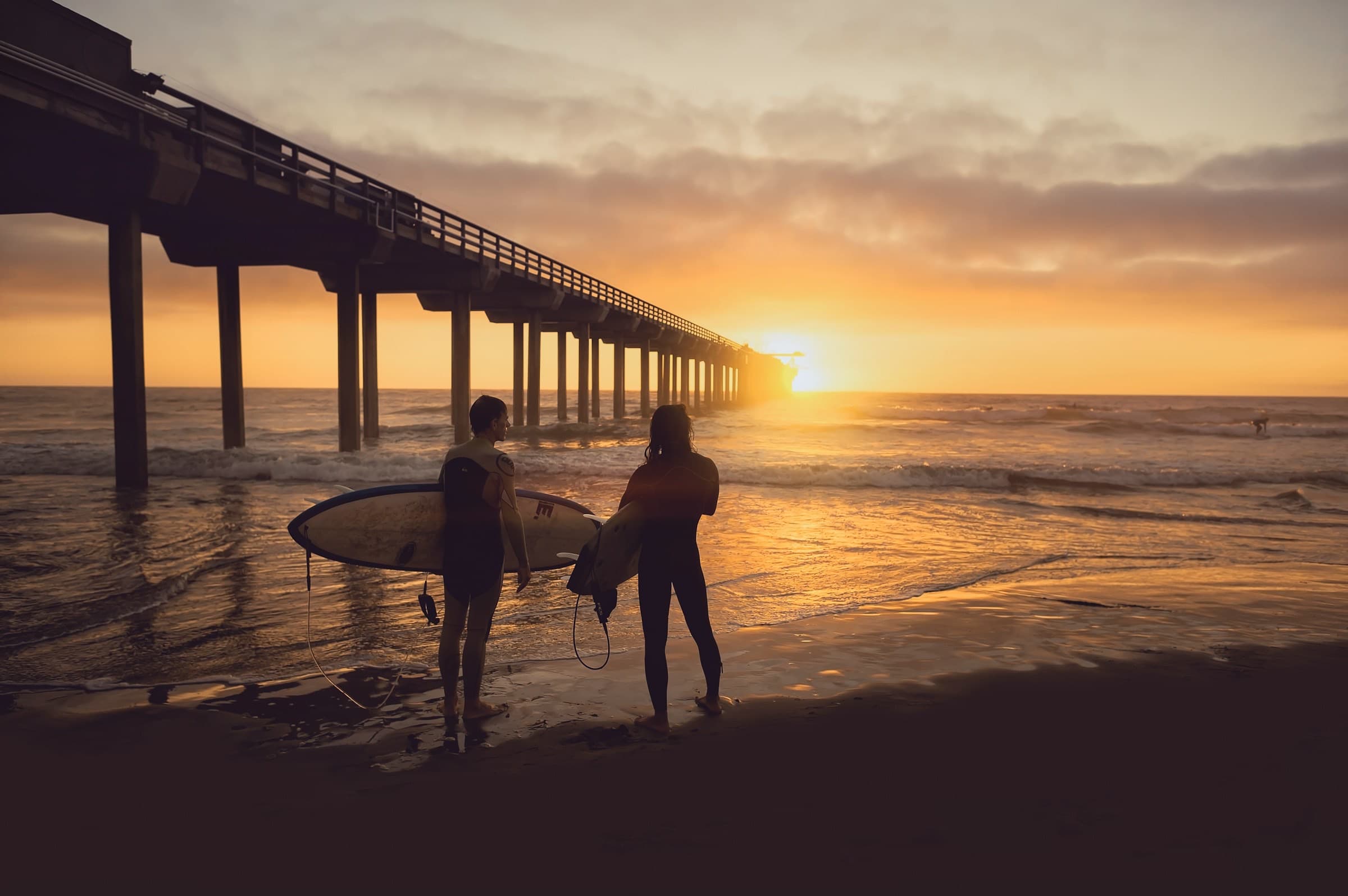 Surfers at the pier during golden hour
